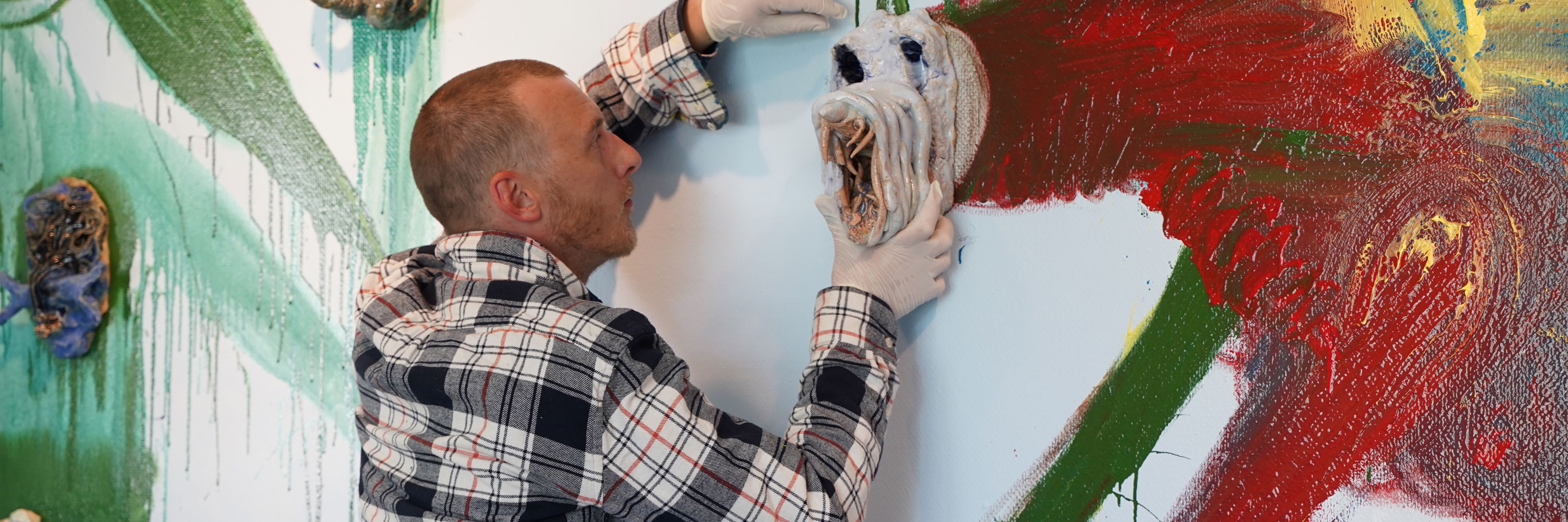 Næblerød monterer maske på vægmaleri