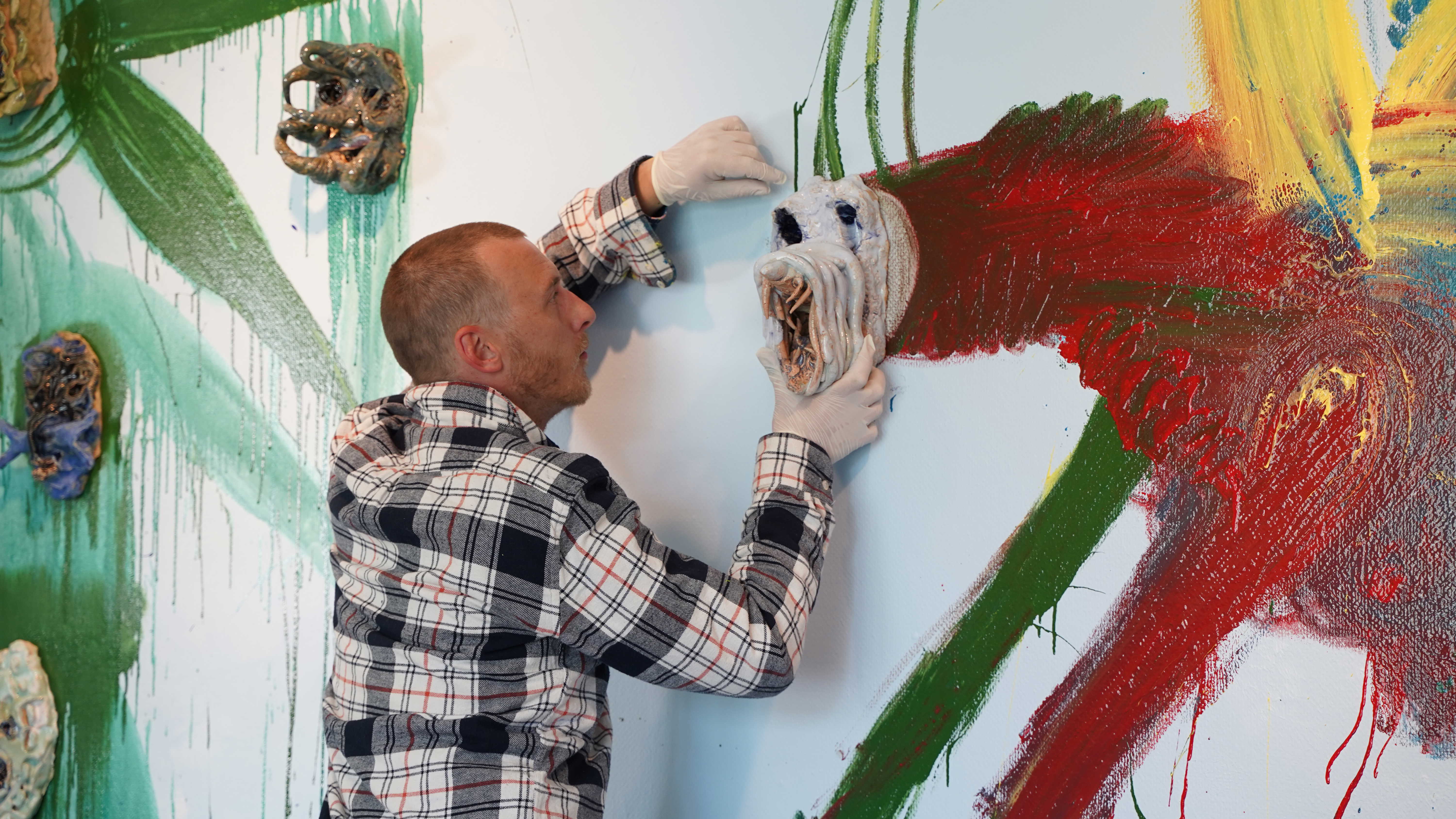 Næblerød monterer maske på vægmaleri