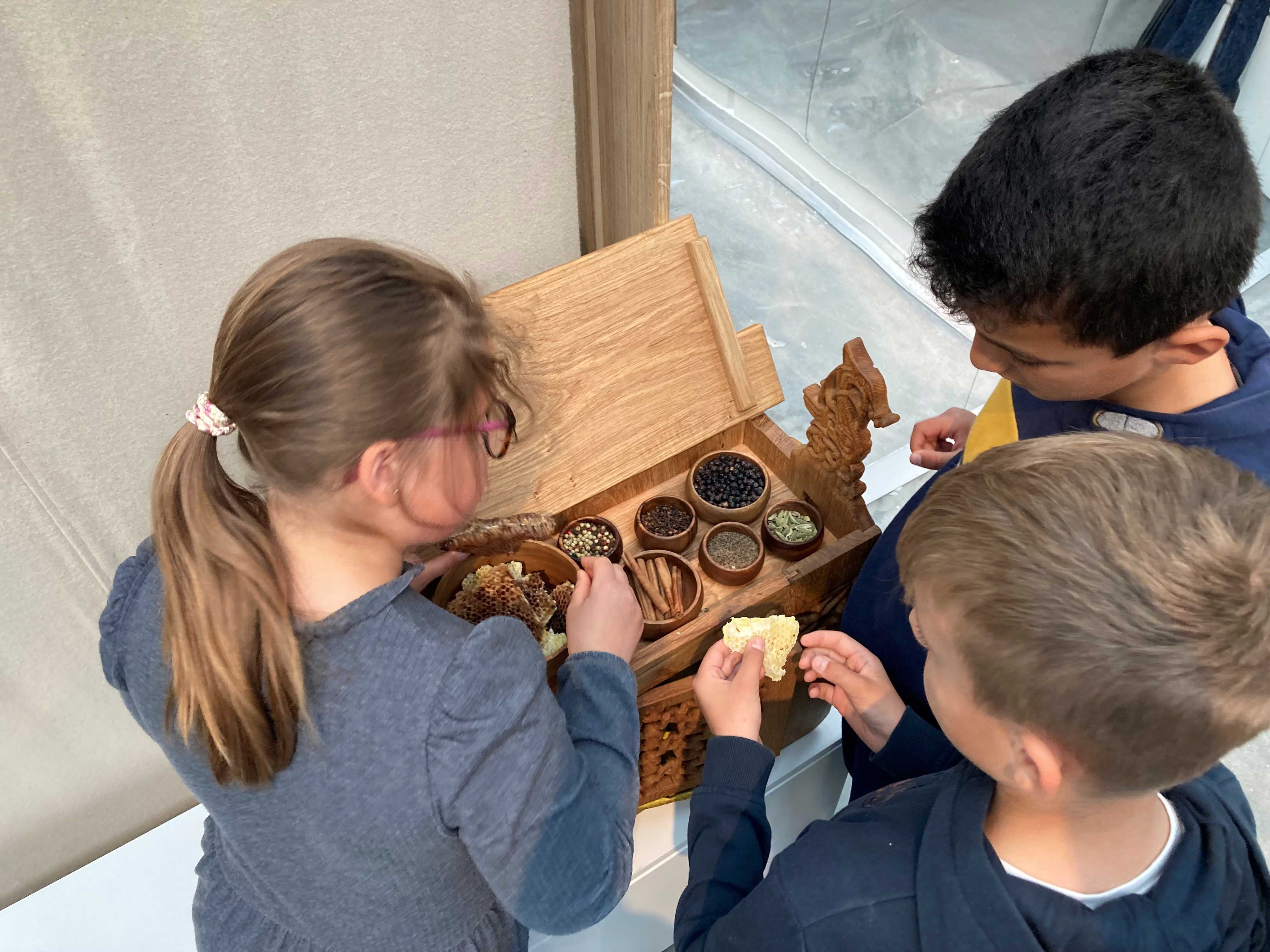 Tre børn dufter og mærker i udstillingen Magt og guld